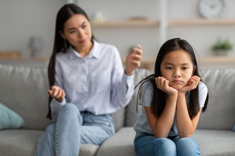 Alt text: Một cặp vợ chồng trẻ tuổi đang ngồi trên ghế sofa, người vợ thể hiện sự lo lắng, người chồng đang an ủi và lắng nghe, ám chỉ sự hỗn láo của con tuổi dậy thì.