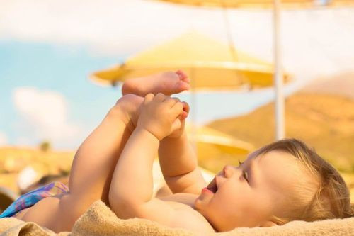 Một em bé đang được tắm nắng nhẹ nhàng dưới ánh sáng tự nhiên để hấp thụ vitamin D.