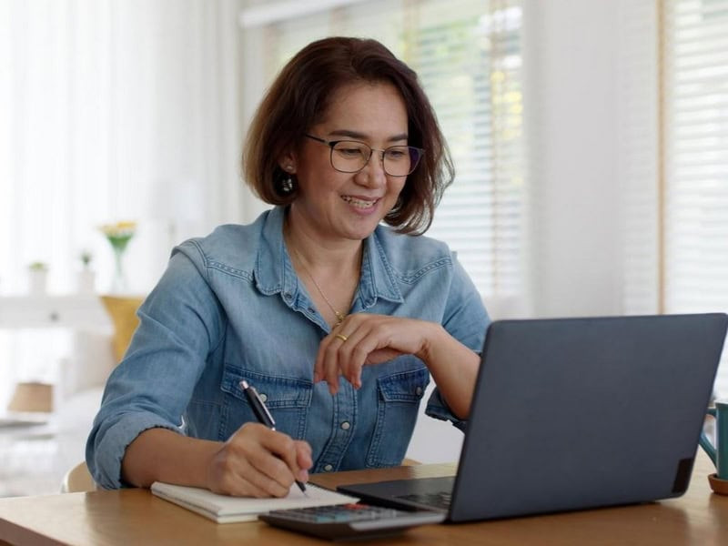 Một người phụ nữ trung niên đang đọc sách, minh họa sự tập trung vào việc học hỏi và nâng cao kỹ năng thay vì thay đổi lớn trong sự nghiệp của nữ Giáp Dần.