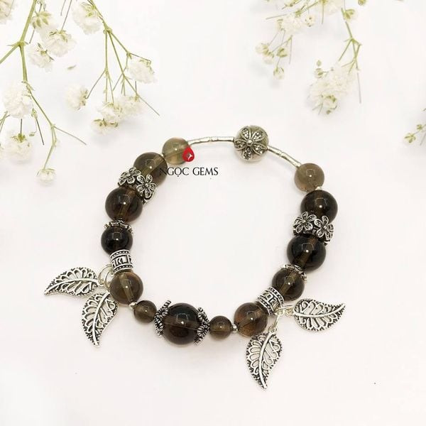 Vòng tay thạch anh khói trên cổ tay, biểu tượng của sự bình an và may mắn cho người đeo.