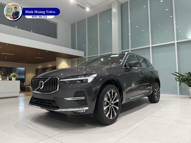 Bức ảnh cận cảnh chiếc xe sang trọng màu xám bạc đang đậu trước một showroom hiện đại.